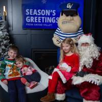Three siblings smile with Santa and Louie